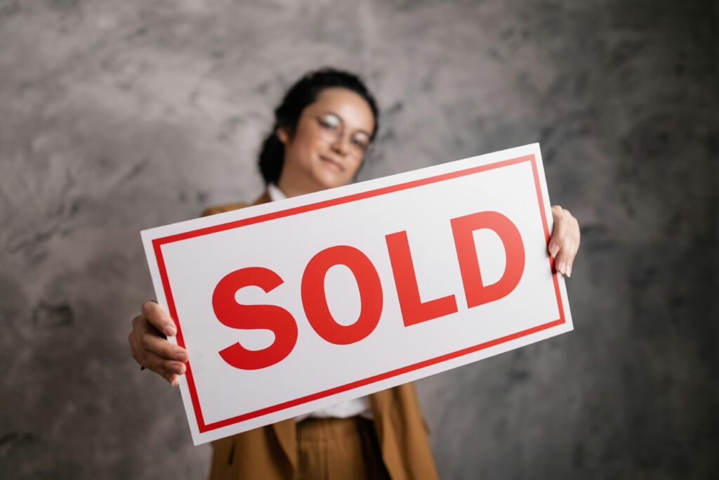 An entry-level salesperson holding a Sold sign